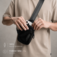Homme ouvrant la sacoche crossbody VALUNE noire au format Mini d'un litre